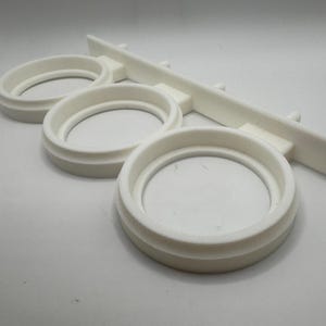 May include: White plastic wall-mounted organizer with three circular slots for holding items.