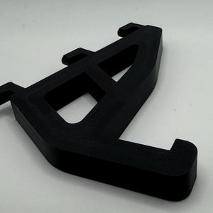 May include: Black plastic 3D printed bracket with three holes and a curved design.