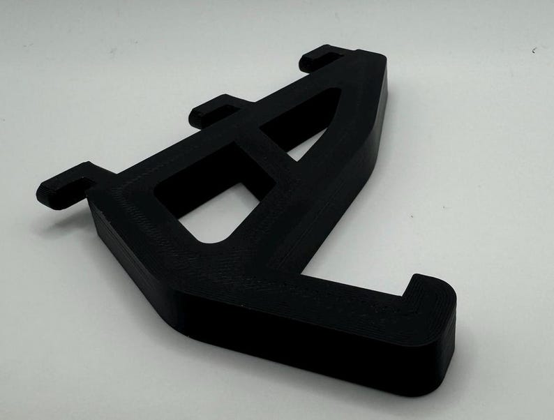 May include: Black plastic 3D printed bracket with three holes and a curved design.