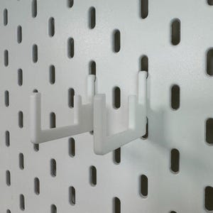 May include: Two white pegboard hooks are inserted into a white pegboard. The hooks are designed to hold items and are made of a durable plastic material. The pegboard has evenly spaced oval holes.