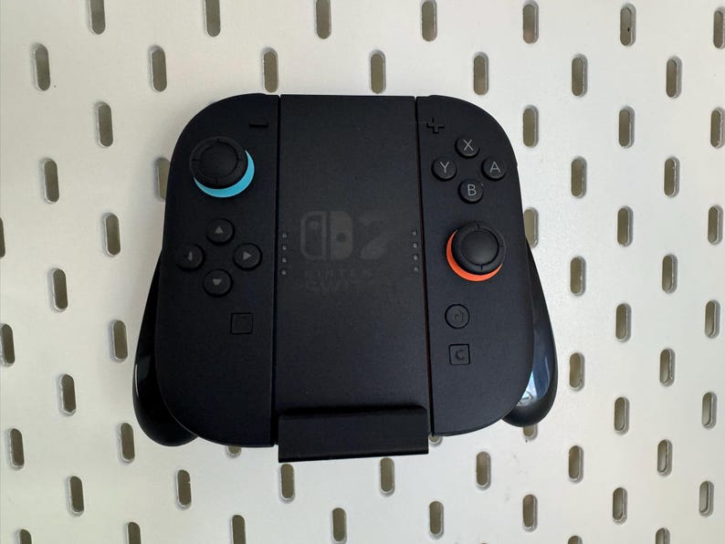 Op de afbeelding: Zwarte Nintendo Switch-controller met blauwe en oranje accenten. Voorzien van knoppen, directionele pads en analoge sticks. De controller heeft het Nintendo Switch-logo en is voor gaming.