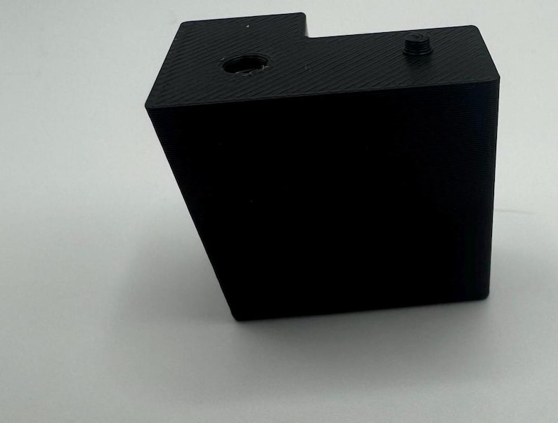 May include: A black plastic box with a small hole on the top and a screw on the side.