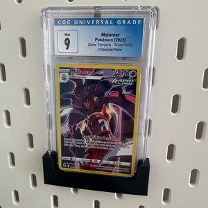 May include: A graded Pokemon card in a clear plastic case. The card is a Malamar from the Silver Tempest set. The card is graded a 9 by CGC, which is considered Mint condition.
