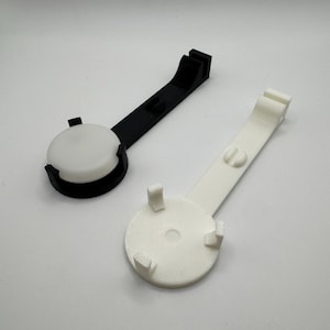 K&ouml;nnte beinhalten: Zwei 3D-gedruckte Telefonst&auml;nder, einer schwarz und einer wei&szlig;. Beide St&auml;nder haben eine runde Basis mit drei Zinken und einen langen Arm.