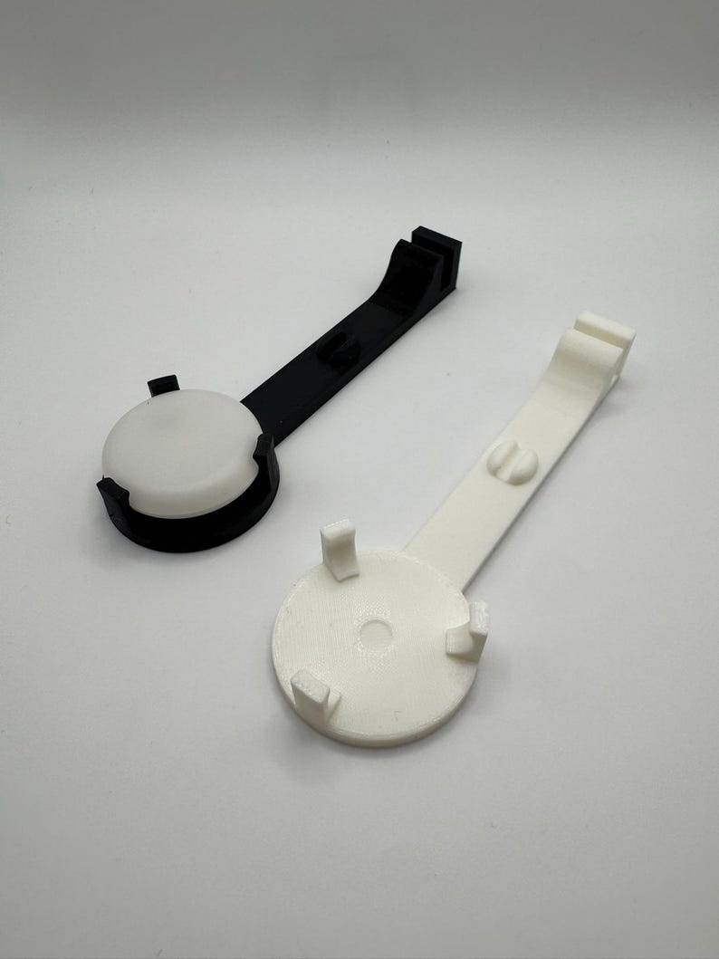 K&ouml;nnte beinhalten: Zwei 3D-gedruckte Telefonst&auml;nder, einer schwarz und einer wei&szlig;. Beide St&auml;nder haben eine runde Basis mit drei Zinken und einen langen Arm.