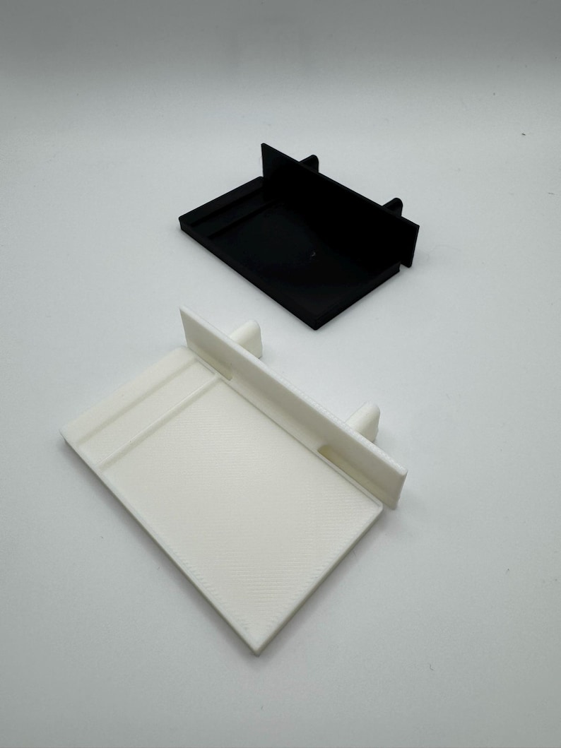 May include: Two 3D printed plastic shelf brackets, one white and one black. The brackets are designed to be used for shelves or other objects.