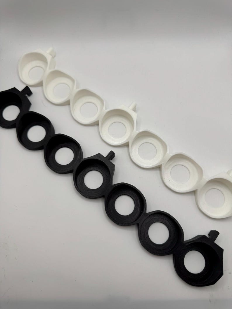 以下が含まれることがあります： 中央に円形の穴が開いた黒と白のプラスチック製のリングが2セット。リングはチェーン状に繋がっています。