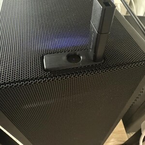 Pu&ograve; includere: Una torre per computer nera con un pannello frontale in rete nera. Un adattatore USB nero &egrave; collegato alla torre.