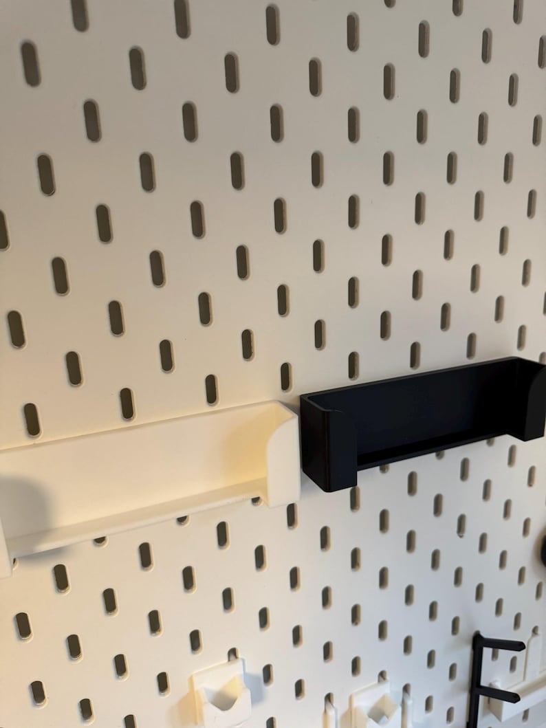 Puede incluir: Panel perforado blanco con agujeros ovalados espaciados uniformemente, con un estante blanco y un estante negro. Los estantes est&aacute;n dise&ntilde;ados para fijarse al panel perforado. El panel perforado es una soluci&oacute;n vers&aacute;til de almacenamiento y organizaci&oacute;n.