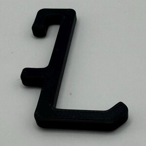 May include: A black plastic hook with a rounded end. The hook is shaped like the letter 'L' and has a textured surface.