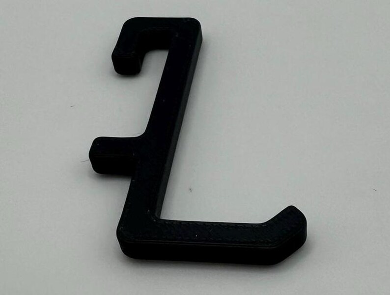 May include: A black plastic hook with a rounded end. The hook is shaped like the letter 'L' and has a textured surface.
