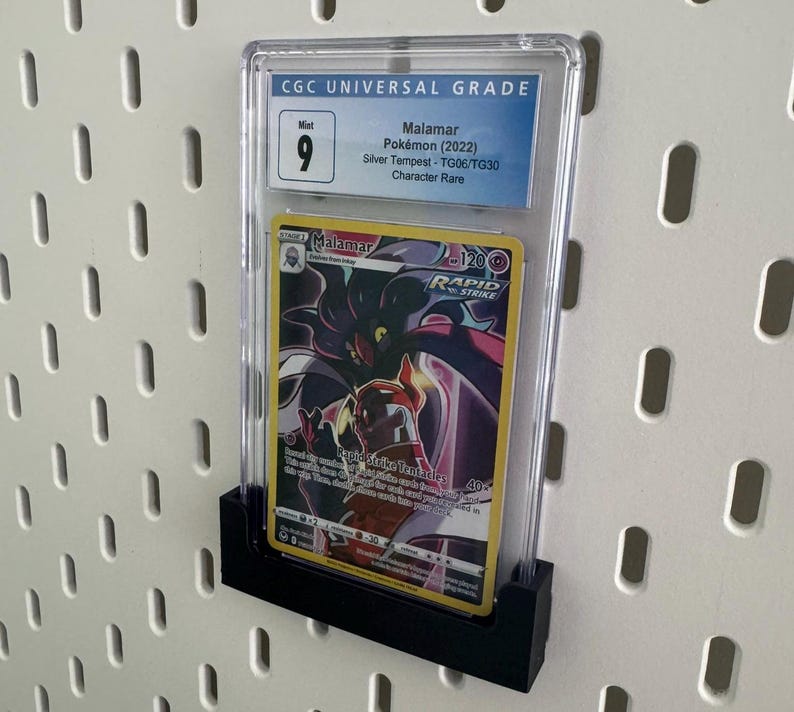 May include: A graded Pokemon card in a clear plastic case with a black backing. The card is a Malamar from the Silver Tempest set and is a Character Rare. The card is graded a 9 by CGC.