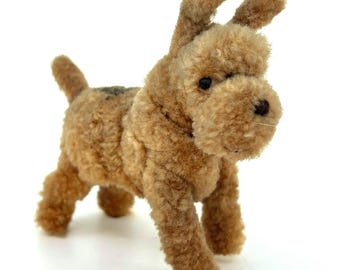 Può includere: Un cane di peluche marrone e beige con una texture soffice. Il cane ha grandi orecchie e un'espressione amichevole.
