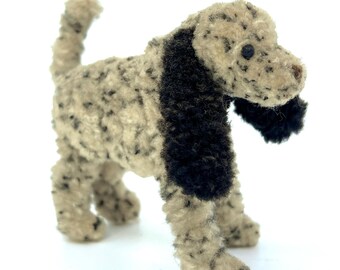 Può includere: Un piccolo cane di peluche con un corpo bianco e nero macchiato e orecchie di pelliccia nera. Il cane è in piedi su tutte e quattro le zampe con la testa inclinata di lato.