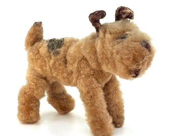 Può includere: Un piccolo cane di peluche marrone e nero con orecchie floppy. Il cane è in piedi su tutte e quattro le zampe e ha un'espressione amichevole.