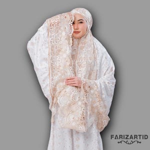 May include: White prayer dress with a floral pattern and lace trim. The dress has a long sleeve and a high neck. The lace trim is a light brown color.