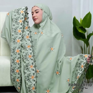 May include: A light green prayer shawl with floral embroidery. The shawl has a scalloped edge and is made of a soft, lightweight fabric.