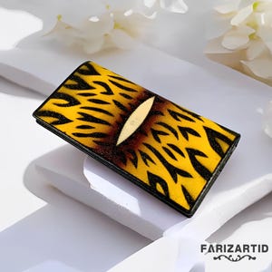 Könnte beinhalten: Eine gelbe und schwarze gemusterte Brieftasche mit schwarzem Rand. Das Muster ähnelt einem Tigerstreifen.