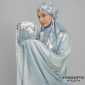 May include: A light blue prayer set with a white floral design. The set includes a headscarf, a matching bag, and a flowing garment. The brand name "FARIZARTID" is printed in the bottom right corner.