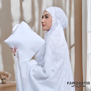 May include: A white prayer garment set, including a head covering and a matching pouch, is shown. The set features delicate floral embroidery and lace trim. The image includes the text "FARIZARTID" in the lower right corner.