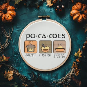 May include: A cross-stitch embroidery hoop with the text "PO-TA-TOES" and three illustrated squares: "BOIL 'EM", "MASH 'EM", and "Stick 'em IN A Stew". The background is dark teal with fall foliage and pumpkins.