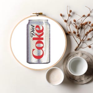 Puede incluir: Una lata de aluminio blanca con letras rojas que dicen "Diet Coke". La lata está sobre un fondo blanco.