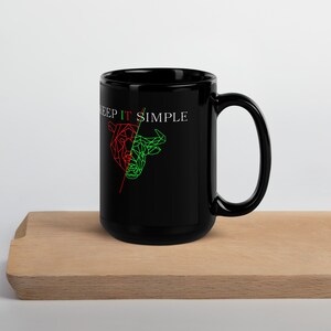 Könnte beinhalten: Schwarze Keramiktasse mit einer weißen Grafik eines roten Bären und eines grünen Bullen mit dem Text "Keep It Simple".