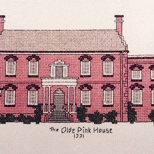 May include: A cross-stitch illustration of a pink house with white trim and multiple windows. The house has a white porch with columns and a black door. The text "The Olde Pink House 1721" is below the house.
