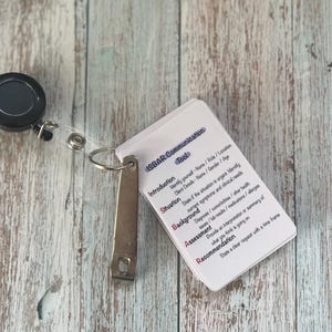 May include: A white card with the acronym ISBAR and the word "Communication" printed in red. The card is divided into five sections: Introduction, Situation, Background, Assessment, and Recommendation. Each section has a brief description of what to include in a communication.