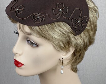 May include: A brown fabric hat with a curved brim and a design of embroidered flowers with rhinestones.
