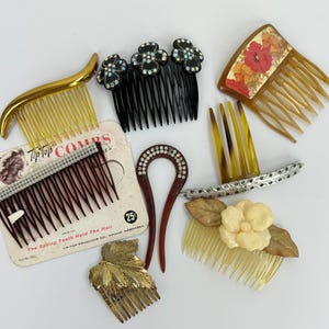 May include: A collection of hair accessories including a gold-tone comb, a black comb with rhinestone flowers, a floral patterned comb, a Tip-Top brand comb on a card, a U-shaped hair pin with rhinestones, a silver-tone comb, and a leaf-shaped comb.