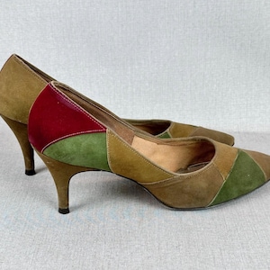 May include: A pair of brown, green, and red suede high-heeled pumps. The shoes have a geometric patchwork design.