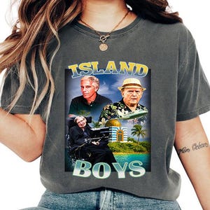 Könnte beinhalten: Dunkelgraues T-Shirt mit einem Aufdruck mit der Aufschrift "ISLAND BOYS" und Bildern von drei Männern. Die Grafik enthält eine tropische Szene mit Palmen und einem Gebäude mit einer goldenen Kuppel. Das Shirt ist ein lässiger Stil.
