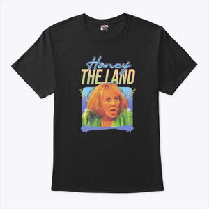 May include: Black t-shirt with the text "Honey The Land" in a neon style font above a colourful image of a woman with a surprised expression. The graphic has a blue and yellow background.