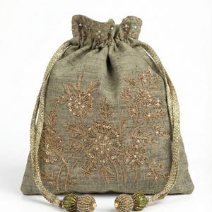 Könnte beinhalten: Ein beigegrüner Beutel mit Kordelzug, goldener Blumenstickerei und Paillettenakzenten. Die Tasche hat goldene Kordelzugbänder und Quasten mit grünen und goldenen Akzenten. Ein stilvolles Accessoire.