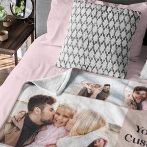 Op de afbeelding: Een wit fleece deken met een collage van familiefoto's. De foto's zijn in een rasterpatroon gerangschikt en tonen een stel en hun kind. Het deken heeft een roze rand en de tekst "Your Custom Text" is afgedrukt in de rechterbenedenhoek.