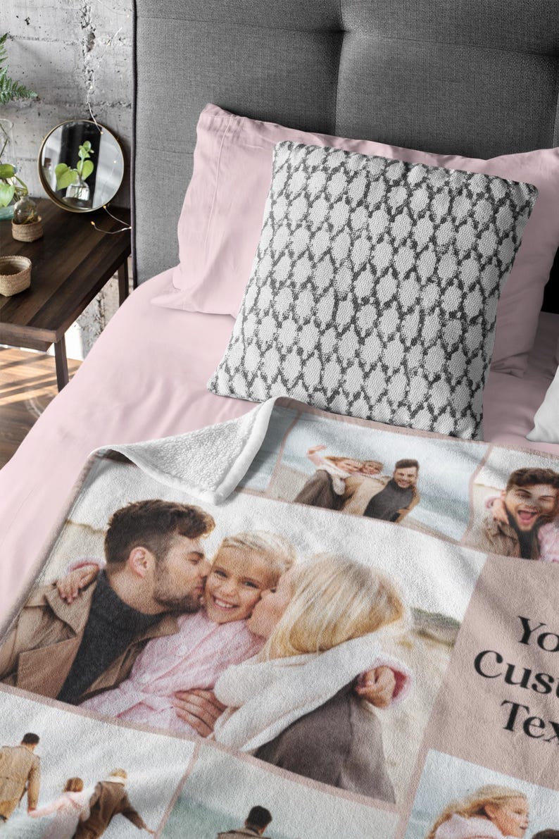 Op de afbeelding: Een wit fleece deken met een collage van familiefoto's. De foto's zijn in een rasterpatroon gerangschikt en tonen een stel en hun kind. Het deken heeft een roze rand en de tekst "Your Custom Text" is afgedrukt in de rechterbenedenhoek.
