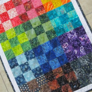 May include: A colorful patchwork quilt with a variety of patterns and colors, including red, green, blue, purple, and orange. The quilt is made up of squares of different fabrics, each with a unique design.