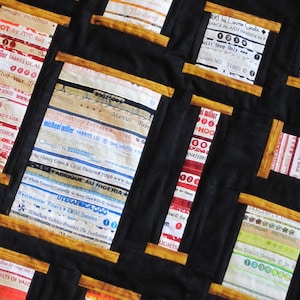 May include: A black fabric background with multiple squares of different colored fabric scraps sewn together. Each square has a different label or tag sewn on top of it. The labels are mostly white with black text. Some of the labels have a copyright symbol and the text "Copyright Protected".