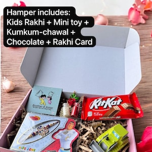 May include: A pink gift box filled with a Kids Rakhi, mini toy, Kumkum-chawal, chocolate bar, and a Rakhi card. The box includes a KitKat bar and a toy truck. The text on the box reads "Kids Zone".