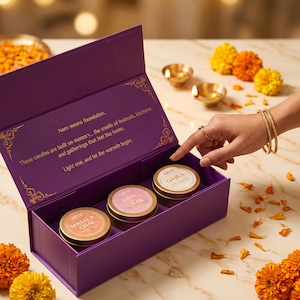 May include: A purple rectangular gift box containing three round gold-colored candle tins labeled Masala Chai, Nani Ghar, and Gajra. The inside lid features gold text reading: Neev means foundation. These candles are built on memory.
