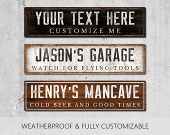 Puede incluir: Tres letreros rectangulares con textura de madera desgastada. El letrero superior dice YOUR TEXT HERE CUSTOMIZE ME. El letrero central dice JASON'S GARAGE WATCH FOR FLYING TOOLS. El letrero inferior dice HENRY'S MANCAVE COLD BEER AND GOOD TIMES.