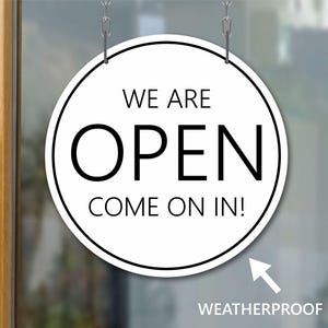 May include: A round, white "OPEN" sign with black text, hanging from a silver chain. The sign reads "WE ARE OPEN COME ON IN!" and has a black border. The word "WEATHERPROOF" is below the sign.