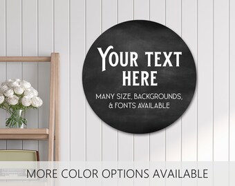May include: A circular black chalkboard sign featuring the white text "YOUR TEXT HERE" followed by "MANY SIZE, BACKGROUNDS, & FONTS AVAILABLE". The bottom of the image includes the text "MORE COLOR OPTIONS AVAILABLE" in a clear sans-serif font.