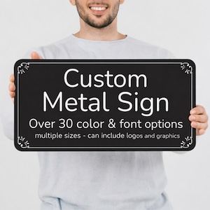 May include: A rectangular black metal sign with rounded corners and white decorative flourishes in each corner. The text reads: Custom Metal Sign, Over 30 color & font options, multiple sizes - can include logos and graphics.