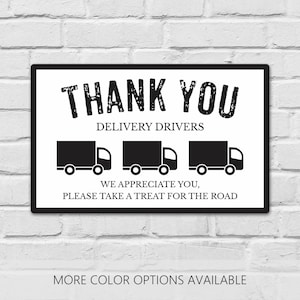 May include: A rectangular white sign with a black border featuring the text THANK YOU DELIVERY DRIVERS in a distressed font, followed by three black truck icons and the text WE APPRECIATE YOU, PLEASE TAKE A TREAT FOR THE ROAD.