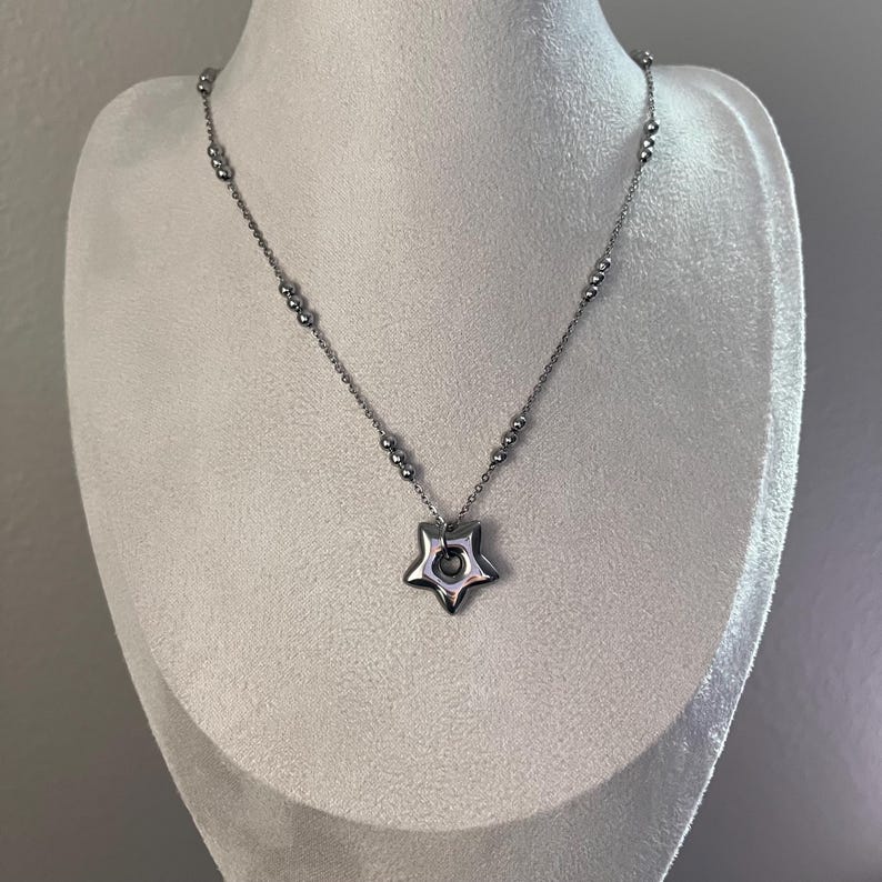 Peut inclure: Un collier en argent avec un pendentif en forme d'&eacute;toile. Le pendentif a un trou au centre.