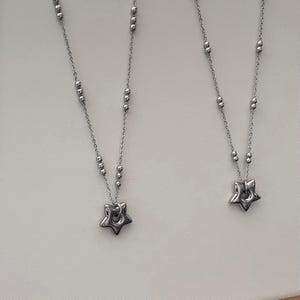 Peut inclure: Deux colliers en argent avec des pendentifs en forme d'&eacute;toile. Chaque collier a une cha&icirc;ne avec de petites perles argent&eacute;es.