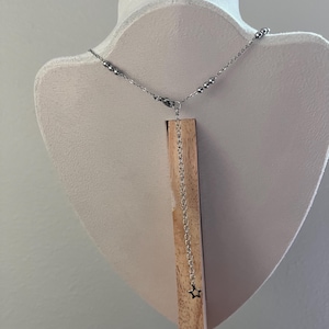 Peut inclure: Un collier en cha&icirc;ne argent&eacute;e avec un petit pendentif en forme d'&eacute;toile suspendu &agrave; l'extr&eacute;mit&eacute;. La cha&icirc;ne est compos&eacute;e de petites perles rondes.