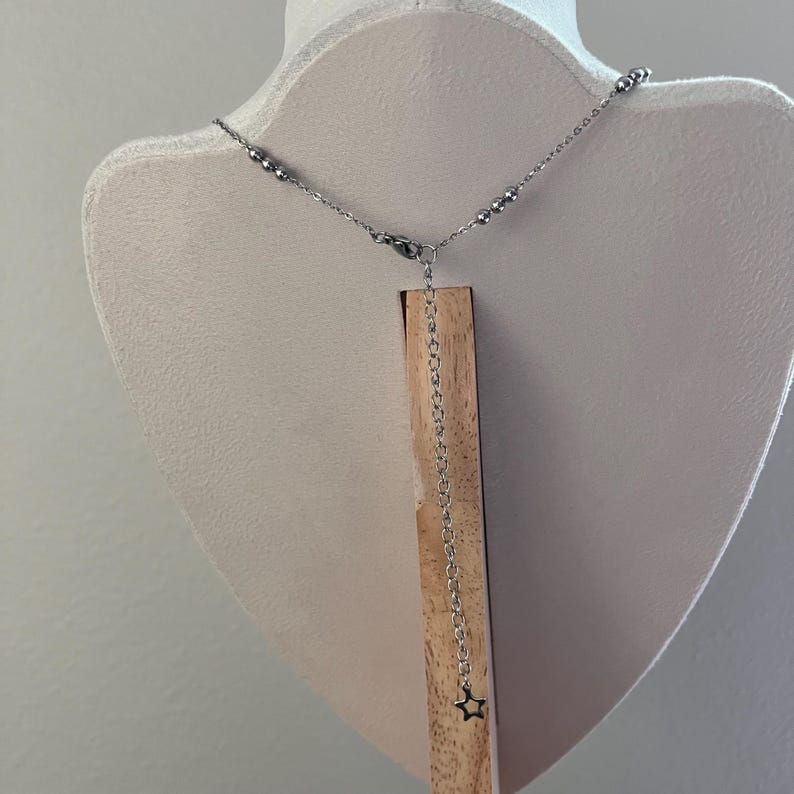 Peut inclure: Un collier en cha&icirc;ne argent&eacute;e avec un petit pendentif en forme d'&eacute;toile suspendu &agrave; l'extr&eacute;mit&eacute;. La cha&icirc;ne est compos&eacute;e de petites perles rondes.
